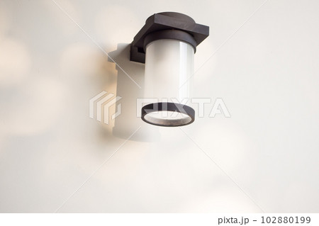 Outdoor cylinder lamp with tree leaves shadow on concrete wall 102880199