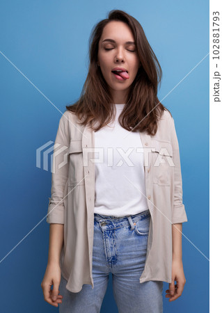 cheerful 30s brunette woman dressed in a shirt with a grimace cheerful 30s brunette woman dressed in a shirt with a grimace 102881793