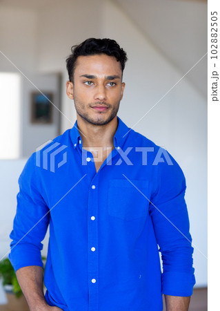 Thoughtful biracial man in blue casual shirt smiling and looking away 102882505