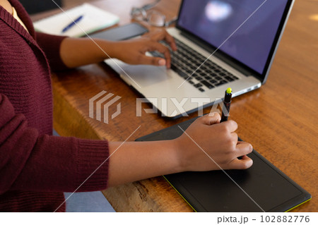 Midsection of plus size african american woman using laptop and drawing tablet Midsection of plus size african american woman using laptop and drawing tablet 102882776