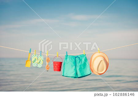 Beach hat, flip-flops and goggles hanging on a clothesline against sea and sky Beach hat, flip-flops and goggles hanging on a clothesline against sea and sky 102886146