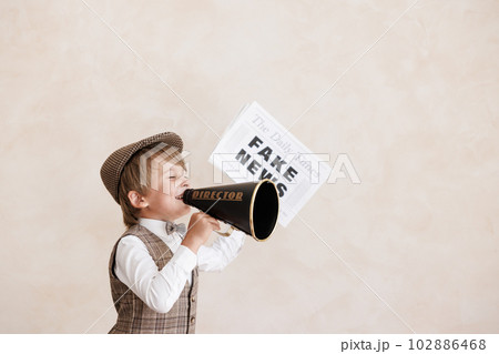 Newsboy shouting against grunge wall background. Boy selling fake news 102886468