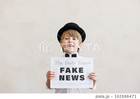 Newsboy shouting against grunge wall background. Boy selling fake news 102886471