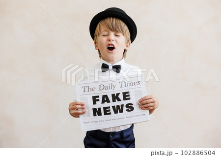 Newsboy shouting against grunge wall background. Boy selling fake news 102886504