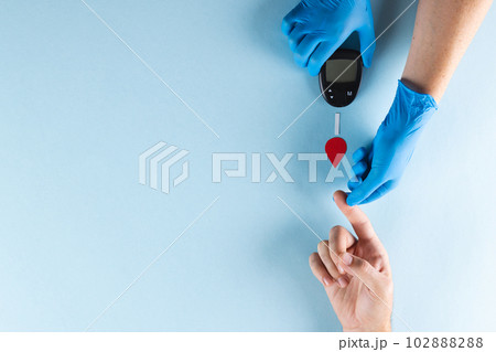 Hands of gloved doctor with glucometer taking blood sugar reading from caucasian woman, copy space Hands of gloved doctor with glucometer taking blood sugar reading from caucasian woman, copy space 102888288