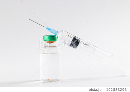 Vial of clear liquid and large syringe on white background 102888298