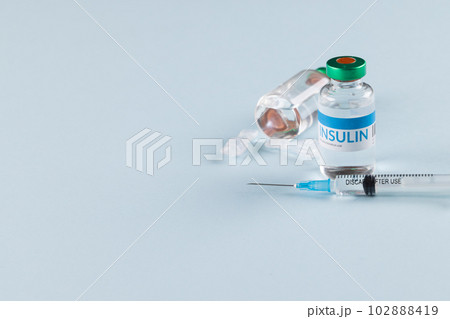 Vials of insulin with caplets and syringe on blue background with copy space 102888419
