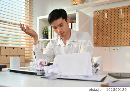 Exhausted male employee working with annual financial report at his workplace. Failure business, overwork concept Exhausted male employee working with annual financial report at his workplace. Failure business, overwork concept 102890126