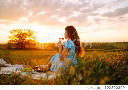 Young woman sits on a plaid with a book. Summer picnic in nature. Healthy food. Young woman sits on a plaid with a book. Summer picnic in nature. Healthy food. 102890809