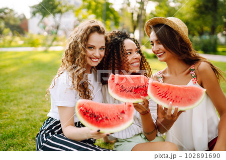 Three young woman have fun together and eating watermelon in hot summer day. 102891690