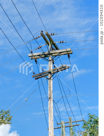 Electric pole and wires, wood electricty pole on blue sky background. 102894810