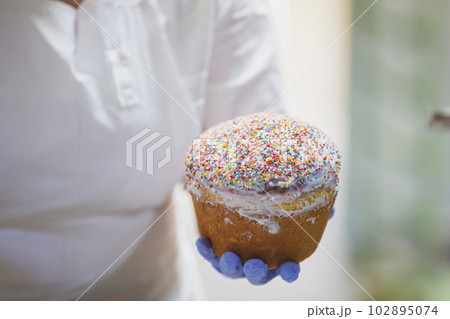 Hands decorate Easter bun. Professional baking Easter cakes. 102895074