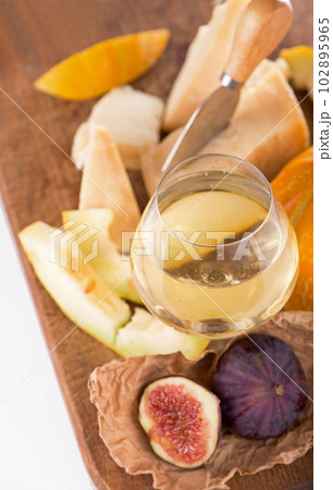 Cheese plate served with grapes, melon, figs, crackers, honey, nuts and white wine on a wooden table Cheese plate served with grapes, melon, figs, crackers, honey, nuts and white wine on a wooden table 102895965