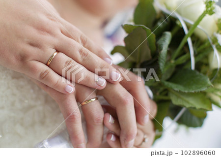Hands of the bride and groom on a wedding bouquet. Wedding day. 102896060
