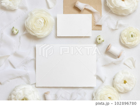 Blank cards near cream roses and white silk ribbons top view, wedding mockup 102896780