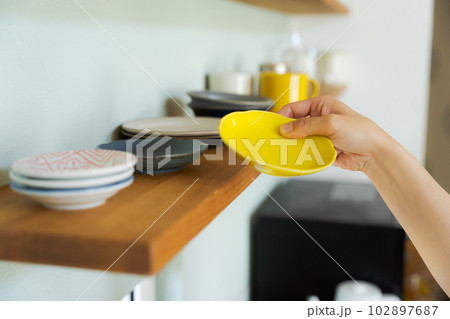 棚に食器を並べる女性の手元 102897687