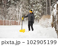 A man in the backyard is clearing the street from deep heavy snow 102905199
