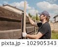 Man builds sections of fence around his yard out of planks 102905343