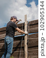 An adult man is engaged in carpentry work at a house construction site 102905344