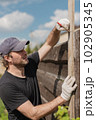 Man builds sections of fence around his yard out of planks 102905345