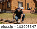 An adult man is engaged in carpentry work at a house construction site 102905347