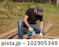 An adult man is engaged in carpentry work at a house construction site 102905348
