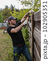 Man builds sections of fence around his yard out of planks 102905351