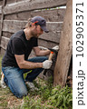 Man builds sections of fence around his yard out of planks 102905371