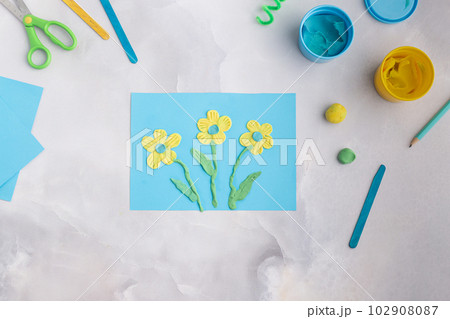 Blue and yellow flowers from plasticine. Kid's craft with dough clay. Colorful clay 102908087