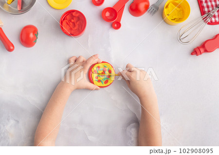 Boy's hands are making pizza with play dough. Kid's plasticine craft for art lesson. Boy's hands are making pizza with play dough. Kid's plasticine craft for art lesson. 102908095
