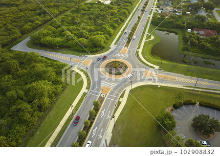Aerial view of road roundabout intersection with moving cars traffic. Rural circular transportation crossroads Aerial view of road roundabout intersection with moving cars traffic. Rural circular transportation crossroads 102908832