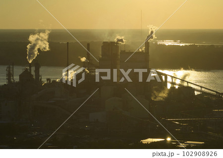 Aerial view of large factory with smokestack from production process polluting atmosphere at plant manufacturing yard. Industrial site at sunset 102908926