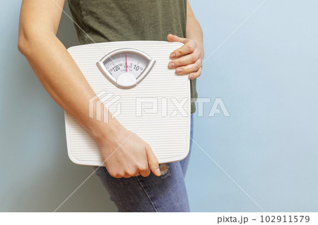 Young woman holding white scales to check the results of her diet 102911579
