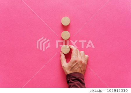 Placing three blank wooden cut circles on pink background Placing three blank wooden cut circles on pink background 102912350