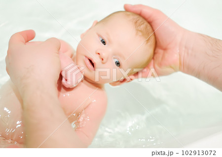 A young father bathes his newborn baby. Parenthood. 102913072