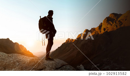 Traveler looks at beautiful sunset among the mountains. 102913582