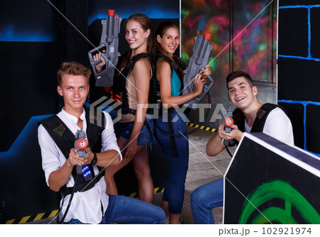 cheerful girls and guys in dark laser tag room cheerful girls and guys in dark laser tag room 102921974