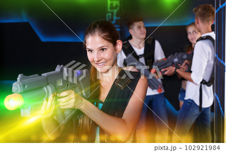 Positive girl with laser pistol during enjoying laser tag game w 102921984