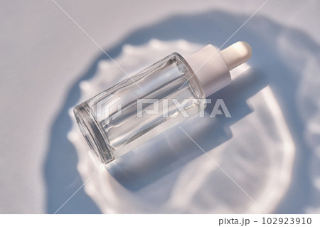Serum bottle on a blue background with glare. 102923910