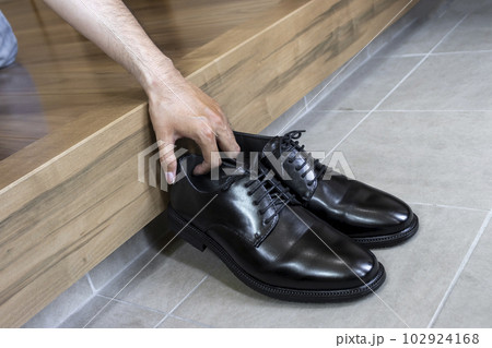 玄関でビジネスシューズを持ち上げる男性の手 玄関でビジネスシューズを持ち上げる男性の手 102924168