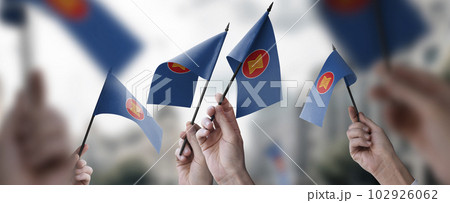 A group of people holding small flags of the ASEAN in their hands A group of people holding small flags of the ASEAN in their hands 102926062