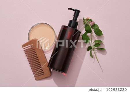 A amber pump bottle with comb, petri dish filled liquid and lantana camara on pink background. Mockup for shampoo of natural extract. Tropical herbal ingredients good for strong and smooth hair A amber pump bottle with comb, petri dish filled liquid and lantana camara on pink background. Mockup for shampoo of natural extract. Tropical herbal ingredients good for strong and smooth hair 102928220