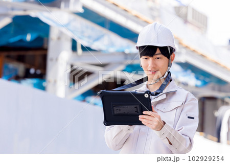 ビジネス　建設現場でタブレットを見る作業服の男性 102929254