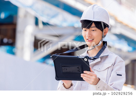 ビジネス　建設現場でタブレットを見る作業服の男性 102929256