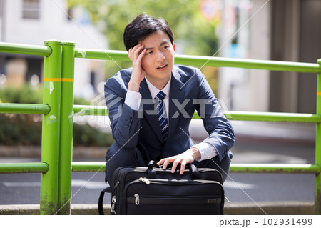 ビジネス　落ち込んで道端に座り込むビジネスマン 102931499