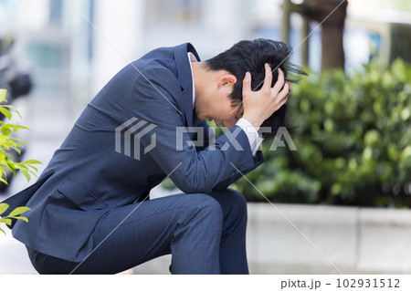 ビジネス　落ち込んで道端に座り込むビジネスマン 102931512