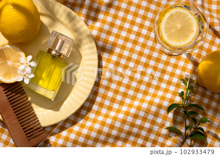 A dish displayed a wooden comb, white flowers and unbranded perfume glass bottle. Decorated with a glass with Lemon slice. Essential oil extracted from Lemon is an ingredient for fragrance production A dish displayed a wooden comb, white flowers and unbranded perfume glass bottle. Decorated with a glass with Lemon slice. Essential oil extracted from Lemon is an ingredient for fragrance production 102933479