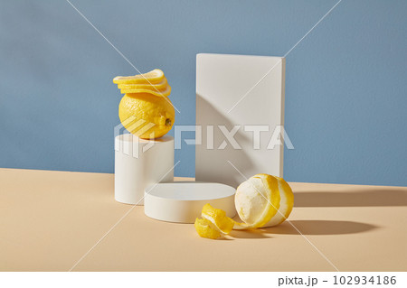 Minimal background with blank space to placed your design or packaging mockups. White empty podium, cylinders geometric and fresh lemons on blue background. Advertising product of lemon extract. 102934186