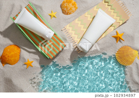 Colorful origami chair and carpet with two empty label tube placed on, decorated with yellow seashells and starfishes. Summer view Colorful origami chair and carpet with two empty label tube placed on, decorated with yellow seashells and starfishes. Summer view 102934897
