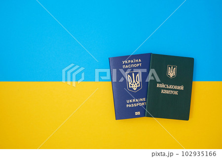 Ukrainian green military ID ticket on the Ukrainian national flag in the top view. Translation 102935166